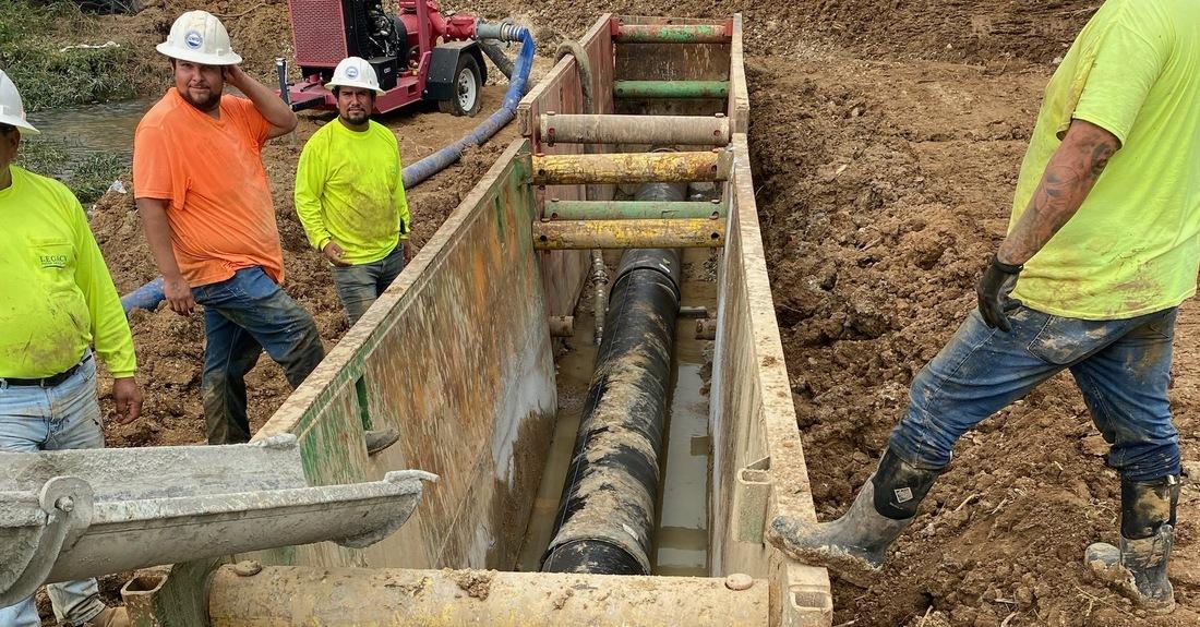 Workers installing a large water main in a construction trench in Athens, Alabama.